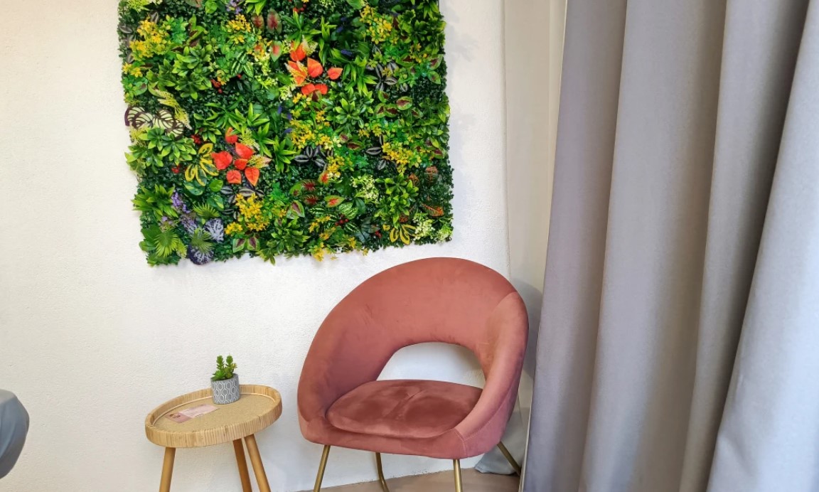 Le coin détente : mur végétal fleuri, fauteuil rose en velours et petite table en rotin